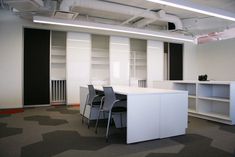 an empty office with white desks and chairs