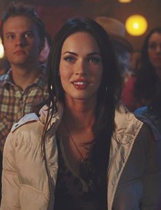 a woman standing in front of a group of people at a bar with lights on