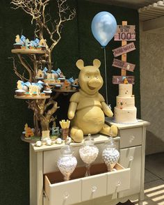 a winnie the pooh birthday party with balloons, cake and desserts on a table