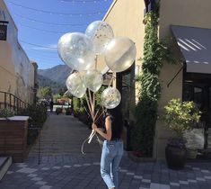 a woman is walking down the street with balloons