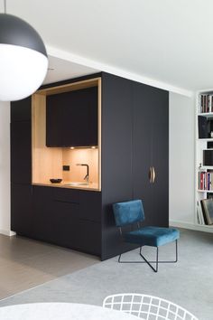 a blue chair sitting in the middle of a living room next to a book shelf