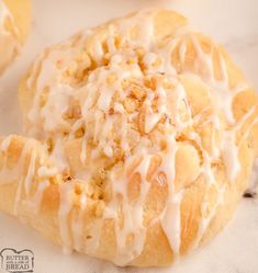 a pastry with icing and nuts on it sitting on a white surface next to other pastries