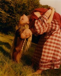 two women are playing in the grass with each other and one is holding her head