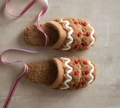 two gingerbread cookies with white icing and red berries on them, tied to a pink ribbon