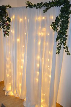 the curtains are covered with white lights and ivys on them, along with other greenery