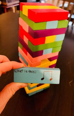 a hand holding a stack of colorful blocks with the word what is this? written on it