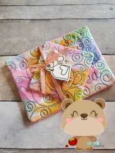 a teddy bear sitting on top of a piece of fabric next to an envelope with a sticker