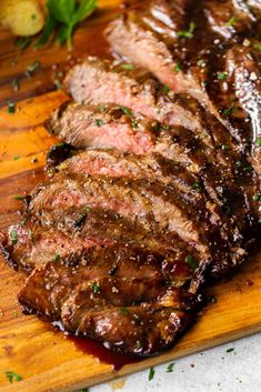 steak sliced up on a cutting board with sauce and parsley