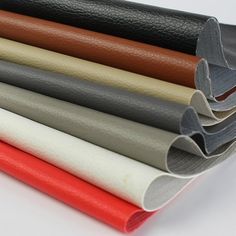 several different colored leathers are stacked on top of each other, with one being rolled up