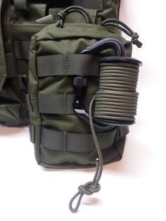 an army green backpack with two cords attached to the back and side pockets on it