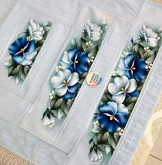 two blue and white flowers are on the side of a table cloth with laces