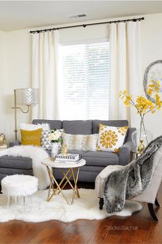 a living room filled with lots of furniture and yellow flowers on the window sill