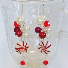 red and white candy canes dangling earrings on clear glass cup with bead accents