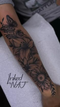 a woman's arm with black and white tattoos on it, flowers and butterflies