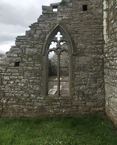 an old stone building with a window in the center and grass growing around it's sides