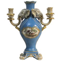 an ornate blue vase with two elephants on it and three candelabra lights