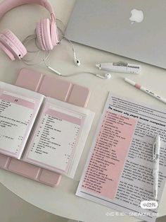 a table with headphones, papers and an apple laptop