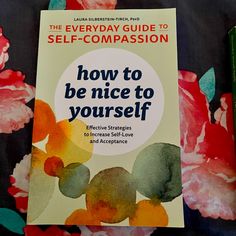 the book how to be nice to yourself is sitting on a bed with pink flowers