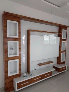 a white and wooden entertainment center in a living room with shelves on each side, tv mounted to the wall