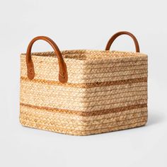 a large woven basket with two handles and leather handles on the handle, sitting against a white background