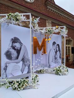 two frames with flowers are on display in front of a brick building and the letter m