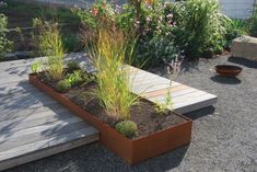 a wooden deck surrounded by plants and flowers