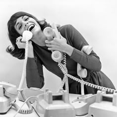 an old photo of a woman talking on the phone while holding two phones in her hands