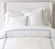 a bed with white sheets and blue trimmings