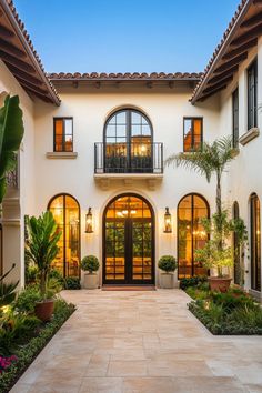 a large white house with lots of windows and plants