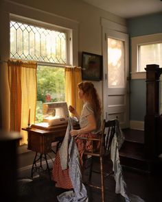 a woman sitting at a desk in front of a window with an ironing board