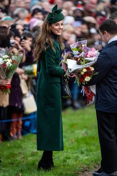 the duke and person are holding flowers in front of a large crowd at an event