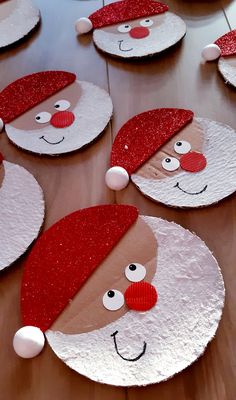 paper plates with santa claus faces and red hats on them sitting on a wooden table