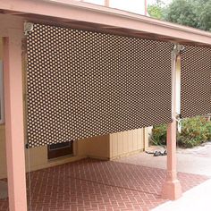 an outdoor patio with a pergolated covering on the side and brick flooring