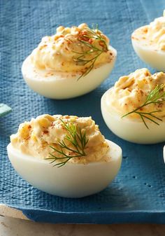 deviled eggs with dill on top are sitting on a blue towel and ready to be eaten