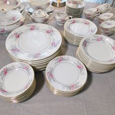 a table topped with lots of white and pink plates covered in floral designs on top of each other