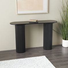 a living room with a rug, table and potted plant