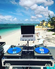 a laptop computer sitting on top of a dj's turntable in front of the ocean