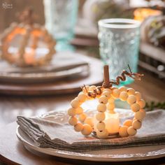 a table set with candles and napkins on it, including a beaded candle holder