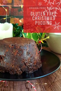 a chocolate cake sitting on top of a black plate next to a candle and christmas decorations