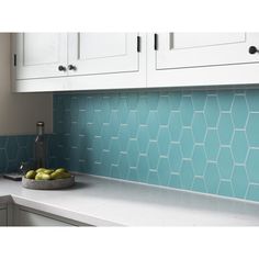 a bowl of fruit sitting on top of a counter next to white cabinets and cupboards