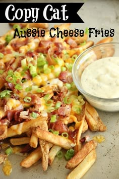 a pile of cheesy fries next to a bowl of ranch dressing