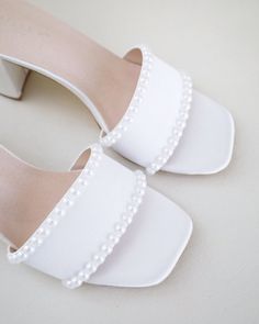 Classic satin slip on block heel sandals adorned with pearls on the vamp for romantic, elegant and feminine look. The delicate pearl beads are placed carefully by hand to create a graceful classic style. Simple and easy wear for bridal wear, bridesmaids, holiday party, wedding parties, and any special occasions. DETAILS: HEEL HEIGHT: 2.5 InchesCOLORS AVAILABLE: Ivory and WhiteUPPER: Synthetic upper and liningMATERIALS: Manmade outsole Sandals With Pearls, Short Heels, Bridal Sandals, Wedding Sandals, Block Heel Sandals, Wedding Parties, Satin Slip, Feminine Look, Block Heels Sandal