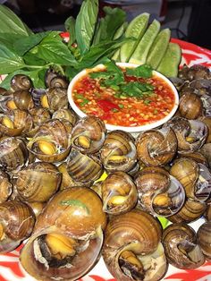 there are many clams on the plate and some sauce is in the bowl next to it