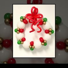 a christmas wreath made out of balloons and red, green and white beads with a bow on it