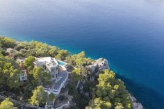 an aerial view of a house on the edge of a cliff with trees surrounding it