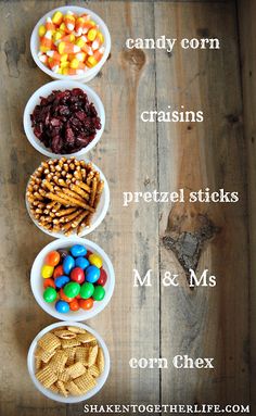 four bowls filled with different types of candy and crackers on top of a wooden table