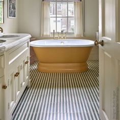 an old fashioned bathtub is in the middle of a bathroom with striped flooring