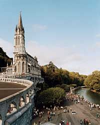 an aerial view of people walking on a bridge over a body of water with a castle in the background