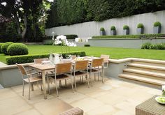 an outdoor dining table and chairs in the middle of a garden with steps leading up to it