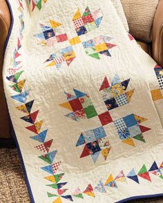 a quilt on a couch with a chair in the background and an appliance showing